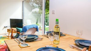 A dining table set with blue plates, wine glasses, and cutlery. A bottle of white wine is on the table. - Yew Tree Cottage (Matlock)