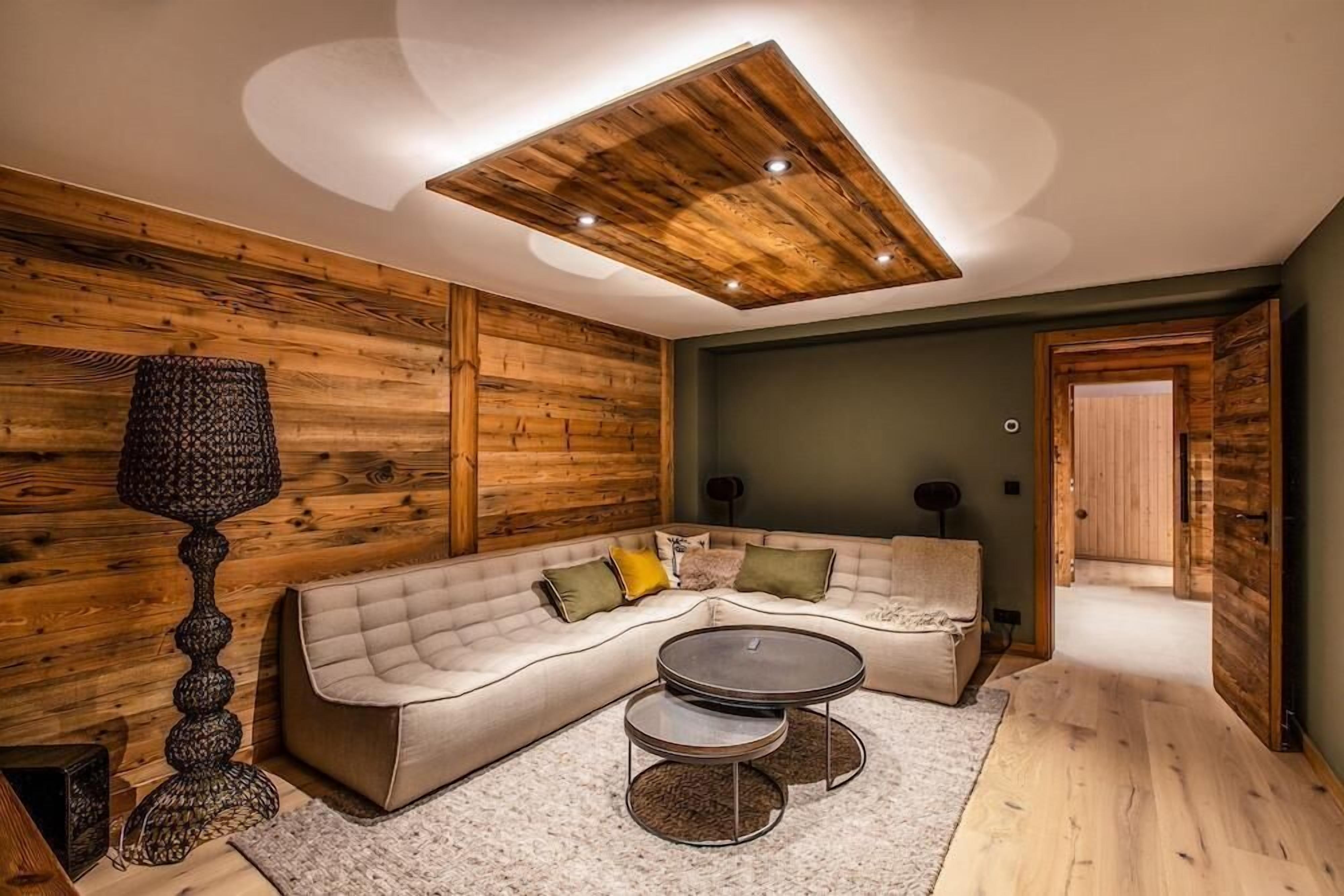 Een gezellige woonkamer met een hoekbank, een ronde salontafel en een bijzonder houten plafond.
