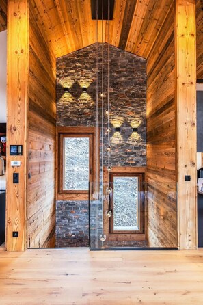 A wooden interior with a stone wall and two windows.