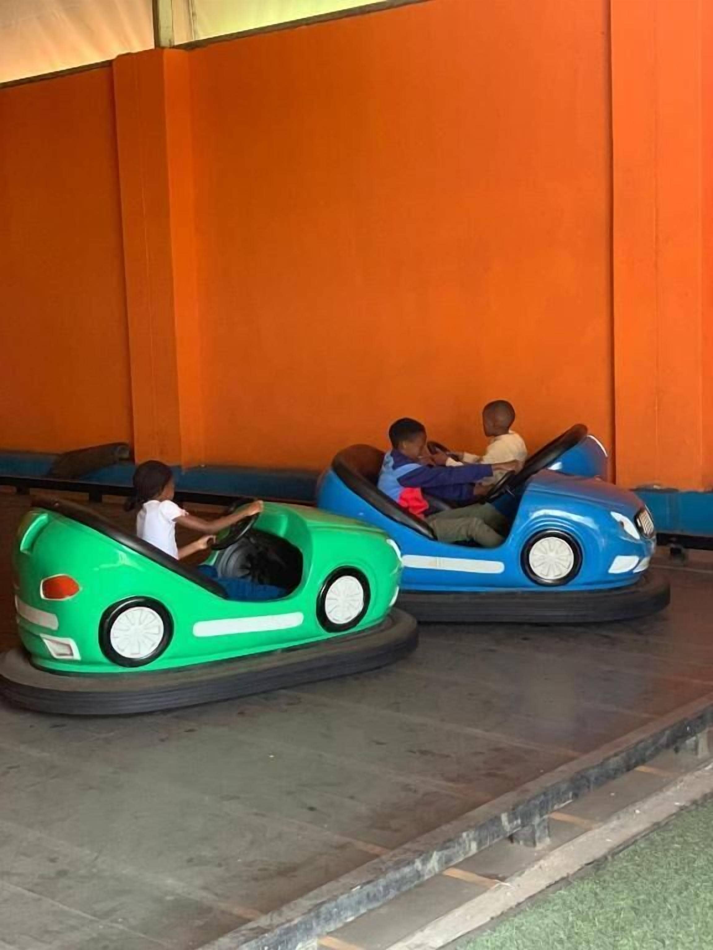 Dois carros bate-bate numa área de diversões com paredes laranja.