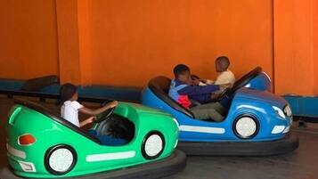 Dois carros bate-bate numa área de diversões com paredes laranja.
