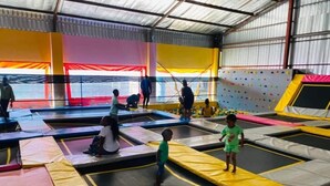 Ein Trampolinbereich im Innenbereich mit mehreren Trampolinen und gepolsterten Flächen.