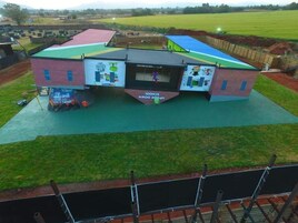 Un edificio multifuncional con campo deportivo, zona cubierta y parque infantil.