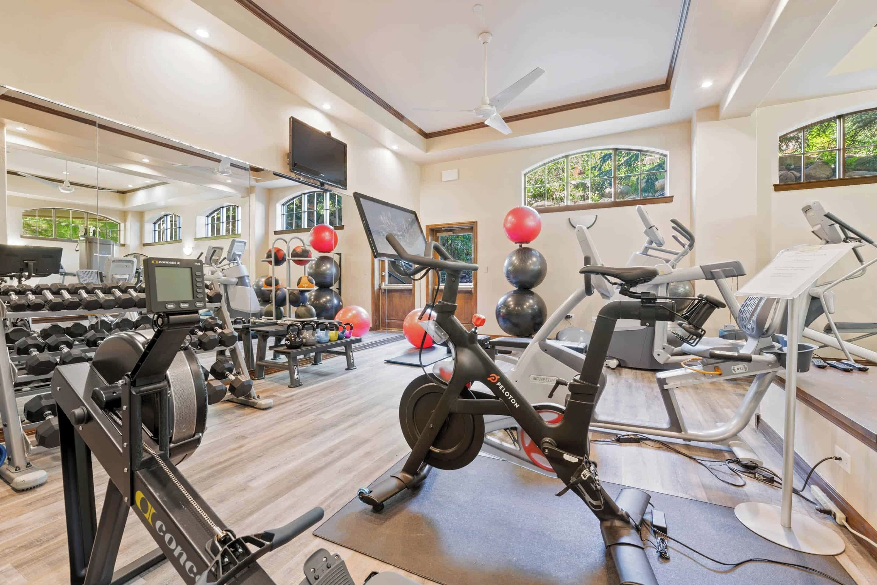 A gym with various exercise equipment, including treadmills, stationary bikes, and weight machines.