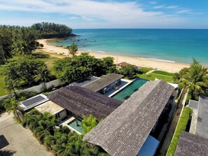 Un resort con varias piscinas, una playa y abundante vegetación.