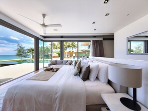 Un dormitorio moderno con una cama grande, ventilador de techo y vistas a una piscina y palmeras.