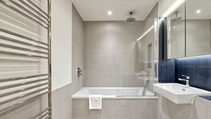 Een moderne badkamer met een bad, een wastafel en een douchecabine met glazen wanden.