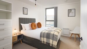 Una camera da letto con un letto, comodino, lampada e vista all'esterno da una finestra.