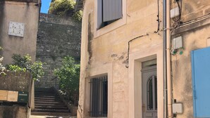 Une rue étroite avec un immeuble doté d’une porte et de fenêtres, d’un vélo et d’un escalier menant à l’étage.