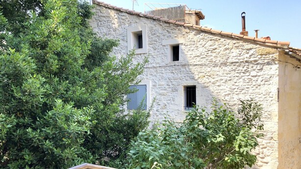 Un bâtiment rustique en pierre, doté de nombreuses fenêtres et d’une balustrade en bois au premier plan.