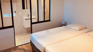 Une chambre moderne avec un grand lit, une salle de bain séparée avec douche et une fenêtre de toit.