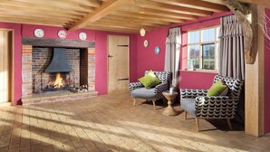 Una sala de estar acogedora con chimenea de ladrillo, vigas de madera y mobiliario estampado.