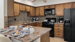 A kitchen with wooden cabinets, a granite countertop, a microwave, a stove, and a refrigerator. - Newly Furnished Sun Drenched Duplex Private Deck Steps to the Beach & Boardwalk! (Seaside Heights)
