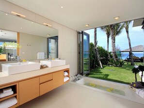 A modern bathroom with two sinks, a large mirror, and a view of a tropical garden and ocean. - Luxe Vacay Beachfront Sava Villa 2 | Villa Amarelo | Chef & Staff | LTH-13 (Phuket)