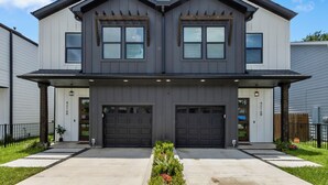 A two-story house with a symmetrical facade, two garages, and a front porch with a planter. - Luxury 4BR Escape 10mins to NRG stadium, Dwtn HTX, MedCtr, and the Zoo! (Houston)
