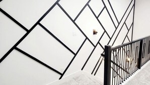 A staircase with a geometric wall design and a black railing. - Luxury 4BR Escape 10mins to NRG stadium, Dwtn HTX, MedCtr, and the Zoo! (Houston)