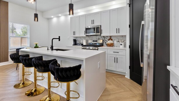 A modern kitchen with white cabinets, stainless steel appliances, and a central island with bar stools. - Luxury 4BR Escape 10mins to NRG stadium, Dwtn HTX, MedCtr, and the Zoo! (Houston)