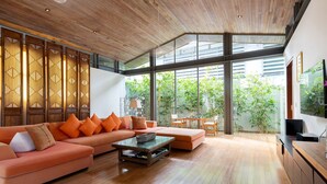 A spacious living room with a wooden ceiling, large windows, a sofa set, and a dining area. - Luxe Vacay Beachfront Sava Villa 5 | Villa Malee Sai | Chef & Staff | LTH-16 (Takua Thung)