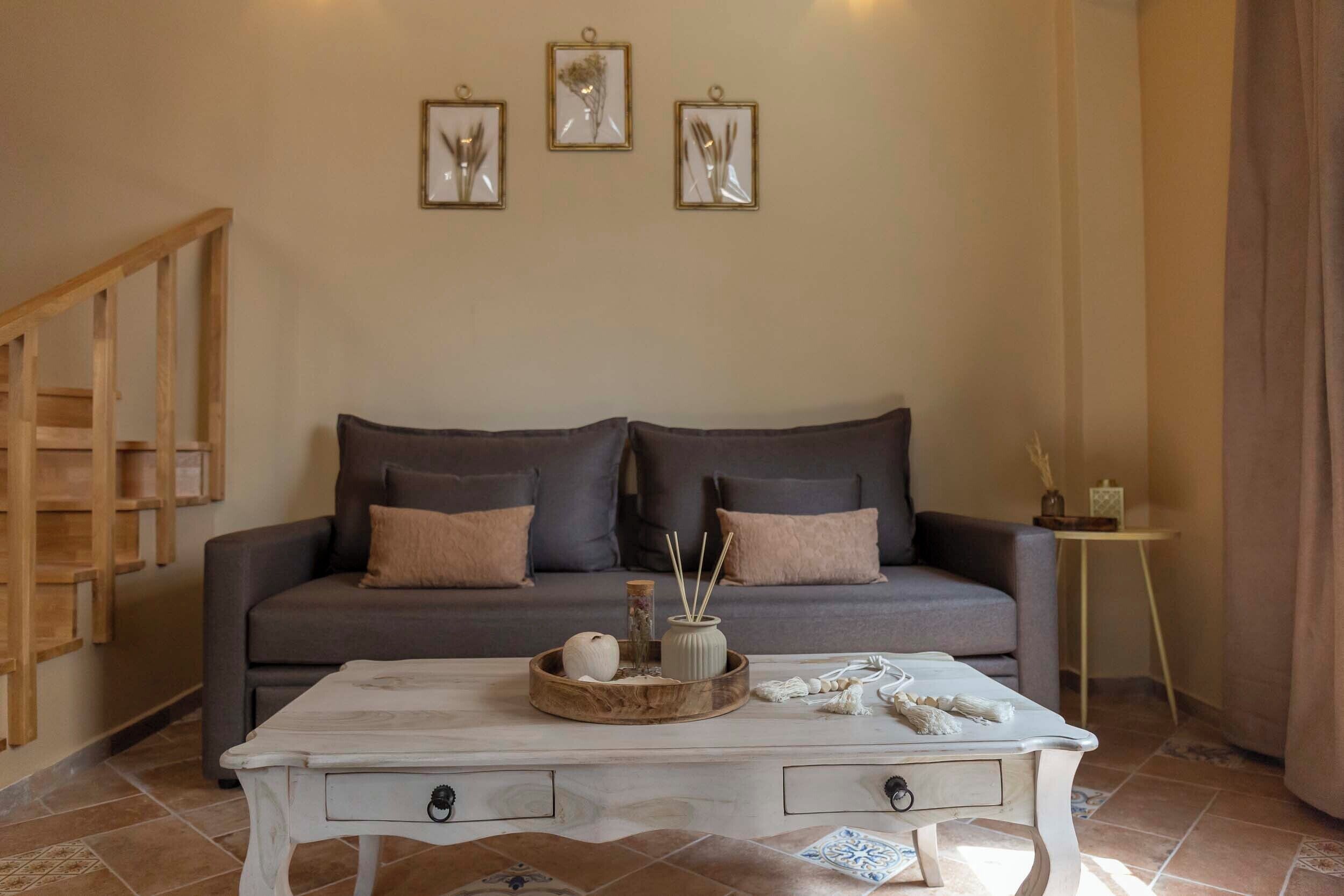 A living room with a grey sofa, a white coffee table with drawers, and a wooden sideboard.