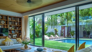 Una sala de estar moderna con un amplio ventanal, una piscina y una estantería bien surtida.