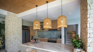 Una cocina moderna con una isla grande, taburetes de bar de madera y lámparas colgantes de mimbre.