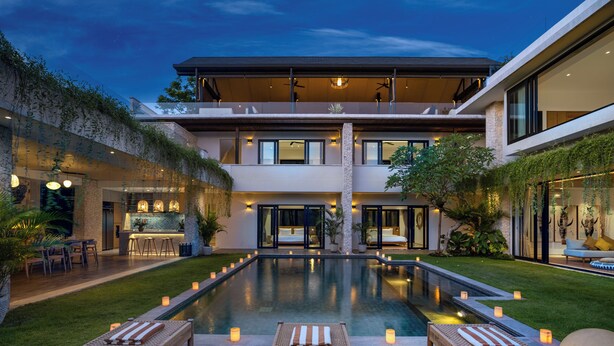 Una casa moderna de varios pisos con piscina, mobiliario exterior y zona de bar.