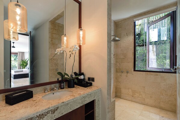 A modern bathroom with a large mirror, pendant lights, a sink, and a shower.