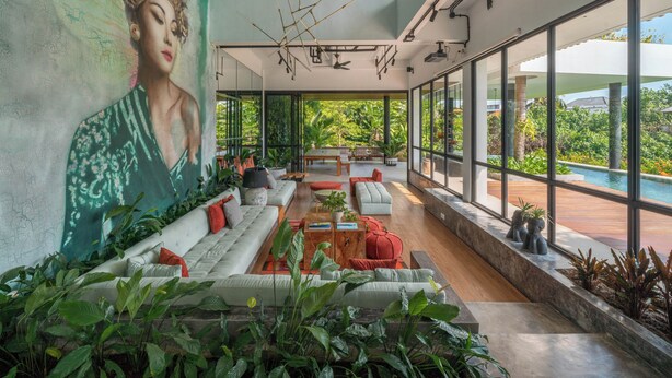 Ein modernes Interieur mit einer großen Wandmalerei, einem Pool und viel Grün.