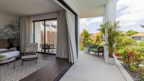 Ein modernes Wohnzimmer mit großem Fenster, einer Couch, einem Sessel und einem Essbereich.