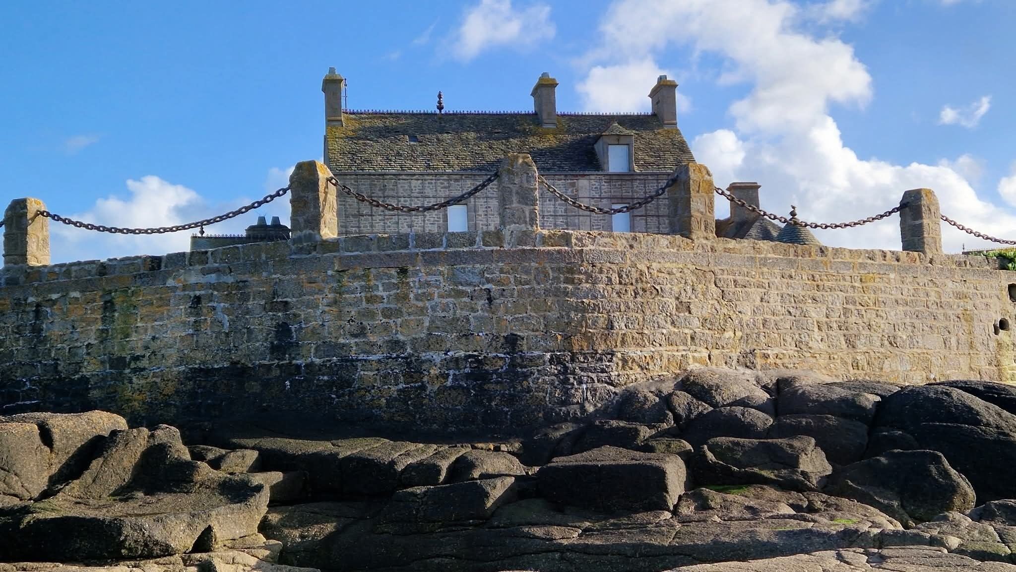 A stone castle with a stone wall and chain-link fence.