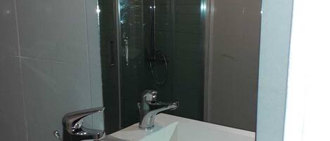 Une salle de bain moderne dotée d’un grand miroir, de deux lavabos et d’une douche à parois de verre.