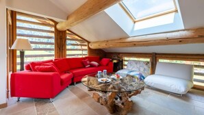 A cozy room with a red sofa, a white armchair, and a glass coffee table. - Wifi, 2nd floor, balcony, fireplace or stove, tv, ski locker, 85m², Le Grand Bornand (Le Grand-Bornand)