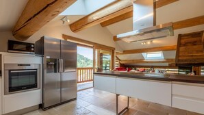 A modern kitchen with a built-in oven, a large refrigerator, and a wooden ceiling. - Wifi, 2nd floor, balcony, fireplace or stove, tv, ski locker, 85m², Le Grand Bornand (Le Grand-Bornand)