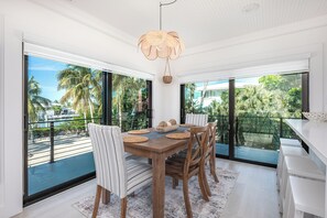 A dining area with a large table, chairs, and a hanging light fixture.