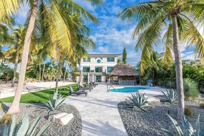 A resort with a swimming pool, palm trees, and a large building with a circular window.