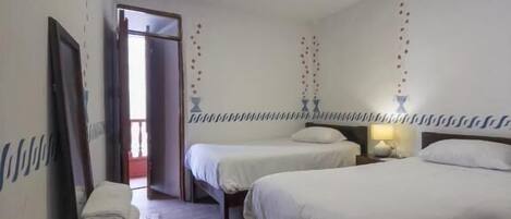 Una habitación de hotel con dos camas individuales, una mesita de madera con artículos de aseo y una lámpara en el techo.