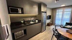 Une cuisine moderne équipée d’un four à micro-ondes, d’un four, d’un évier et d’un réfrigérateur. Un coin repas avec une table et des chaises est également à disposition.