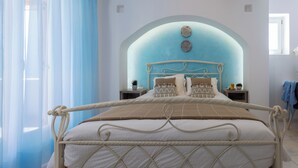 A bedroom with a bed, a headboard, bedside tables, and a window with curtains. - Velonis Villa, Velonis Villas (Naxos)