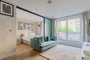 A modern living room with a sofa, a rug, and a large window with curtains.