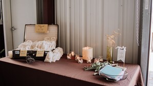 Une table ornée d’une valise ancienne, de bougies et d’un mot de remerciement.