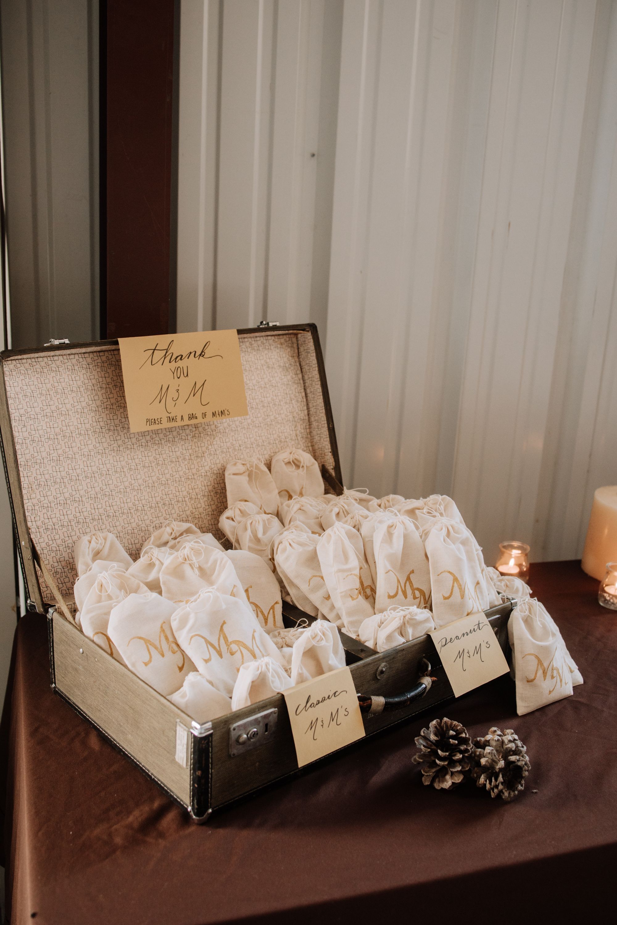 A vintage suitcase filled with white drawstring bags, each with a tag.