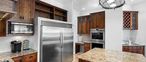 A modern kitchen with wooden cabinets, stainless steel appliances, and a granite countertop.