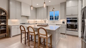 A modern kitchen with a central island, built-in appliances, and pendant lighting.