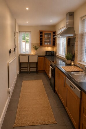 A modern kitchen with wooden cabinets, a built-in microwave, a stainless steel sink, and a large window.