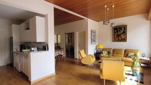 Un espacio habitable amplio con cocina, un sillón amarillo, un sofá y una mesa de comedor.