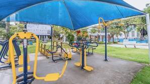 An outdoor gym with exercise equipment under a blue canopy. - Apto Confort vel Tima Localiza o e pet Friendly (Teresópolis)