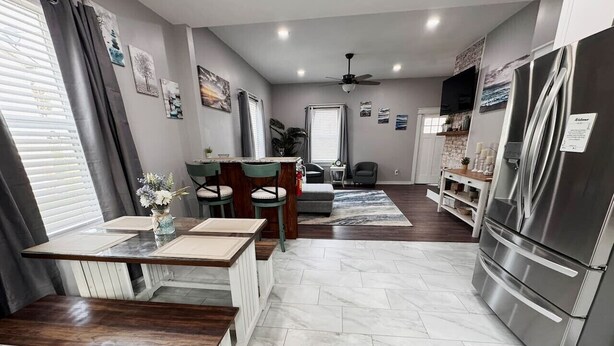 Une cuisine moderne avec un coin repas, un réfrigérateur et un ventilateur de plafond.
