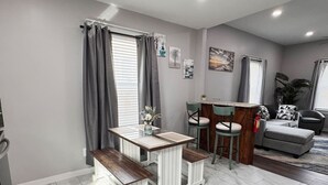 Un salon moderne avec un coin repas, des murs gris et un sol en marbre.