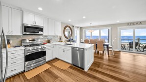 Una cocina moderna con armarios blancos, electrodomésticos de acero inoxidable y suelo de madera.
