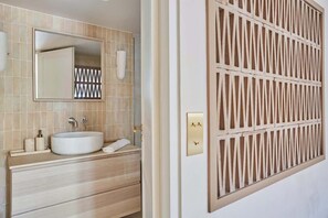 A bathroom with a large mirror, a sink, and a towel rack. - Luxurious Apartment Place Vendome - Rue de la Paix (Paris)